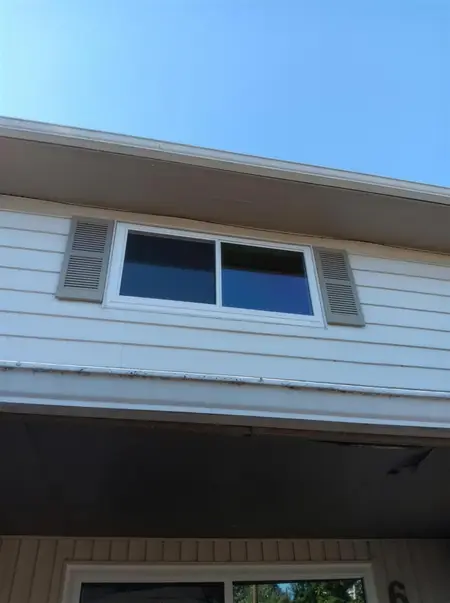 White slider window with shutters above a porch